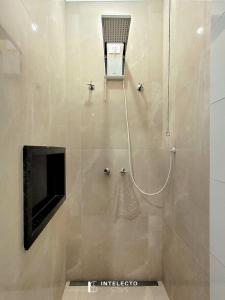 a bathroom with a shower with a chair and a television at Casa - Centro Px Matriz c/ Churrasqueira, 2 Suítes in Poços de Caldas +32 photos