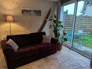 a living room with a brown couch and a plant at Charmante maison près des châteaux de la Loire avec jardin fermé et animaux bienvenus - FR-1-590-65 in Saint-Hilaire-Saint-Mesmin