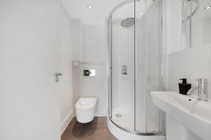 a white bathroom with a shower and a toilet at Hermitage Road Apartment By Morethanstays in London +24 photos