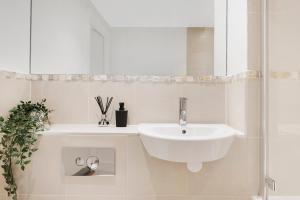 a white bathroom with a sink and a mirror at Hermitage Road Apartment By Morethanstays in London