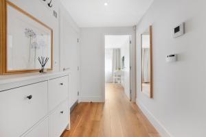 a hallway with white walls and a wooden floor at Hermitage Road Apartment By Morethanstays in London