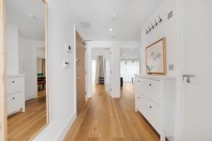 a living room with white walls and a hard wood floor at Hermitage Road Apartment By Morethanstays in London
