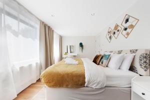 a white bedroom with a large bed and a window at Hermitage Road Apartment By Morethanstays in London