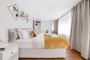 a white bedroom with a bed and a window at Hermitage Road Apartment By Morethanstays in London