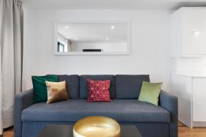 a living room with a blue couch with colorful pillows at Hermitage Road Apartment By Morethanstays in London