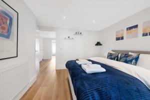 a white room with a blue bed with towels on it at Hermitage Road Apartment By Morethanstays in London