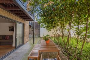 a garden room with a wooden bench and trees at Hermitage Road Apartment By Morethanstays in London