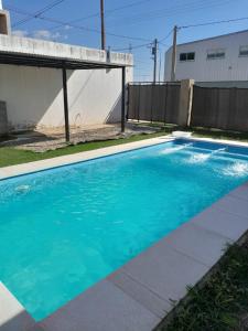a blue swimming pool in front of a house at Casa hasta 6 personas in Villa María