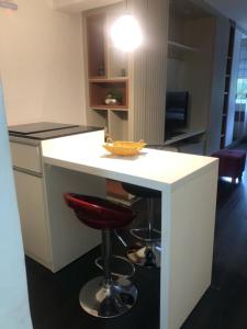 a white kitchen with a bar with a red stool at Rua Dr Diogo de Faria 671 Apto 13 in Sao Paulo +1 photo