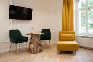 a living room with a yellow chair and a table at Stara Drukarnia Aparthotel in Koszalin