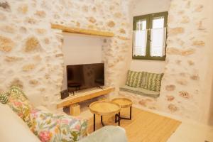 a living room with a stone wall with a tv at Caeli's Home in Gythio