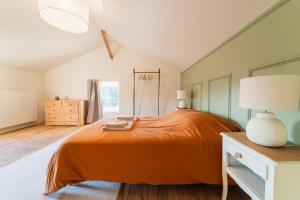 a bedroom with a bed with an orange bedspread at La Pictave, maison poitevine à 5 mn du Futuroscope in Chasseneuil-du-Poitou
