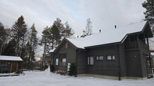 a wooden house with snow on the roof at Elves Eco Design House A in Rovaniemi