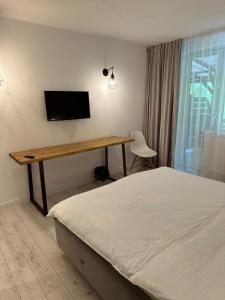 a bedroom with a bed and a desk with a television at Terasa Baniei in Bucovăţ