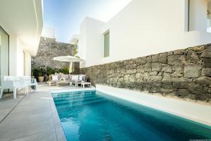 a swimming pool in a house with a stone wall at Villa Eva - amazing heated pool, chill out and BBQ in Callao Salvaje