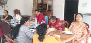 eine Gruppe von Menschen, die um einen Tisch herum sitzen in der Unterkunft Rajlaxmi Resort - Pure Veg in Bolpur