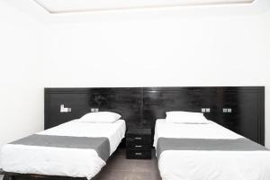 two beds in a room with white walls at Airport INN Hotel in Lomé +9 photos