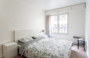 a white bedroom with a bed and a window at Appartement champ elysee in Neuilly-sur-Seine