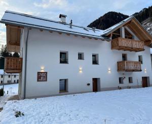 a white building with a balcony in the snow at Locanda al Toal in Moena