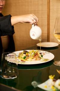 a woman is pouring sauce onto a plate of food at CALEA Boutique Hotel in Bacoli