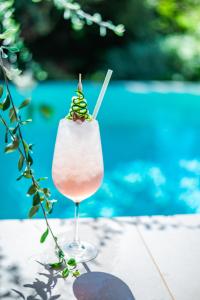 a drink in a wine glass next to a pool at Nestor Luxury Villas in Romanu