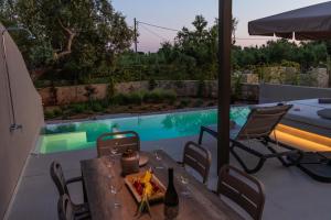 a patio with a table and chairs and a pool at Nestor Luxury Villas in Romanu