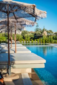 a pool with a row of umbrellas and a swimming pool at Nestor Luxury Villas in Romanu
