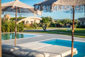 a swimming pool with umbrellas in front of a house at Nestor Luxury Villas in Romanu