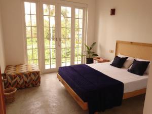 a bedroom with a large bed and large windows at Balazo in Ahangama