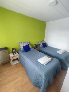 two beds in a room with a green wall at Mil5inco Al Lago in El Calafate