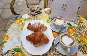 a table with a plate of food and two cups of coffee at Hasu Rental Rooms in Trani