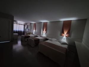a room with three beds and lights on the wall at Hotel Descanso in São Miguel dʼOeste