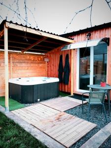 a hot tub and a table in front of a building at Chalet Cosy avec option Jacuzzi in Saint-Genès-de-Fronsac