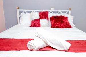 un letto bianco con coperte e cuscini rossi e bianchi di 2 bedroom Stylish Apartment, Kisumu a Kisumu