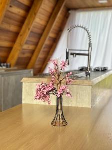 a vase with pink flowers sitting on a table at Cabana Azaléia - Vale do Funil in Taió