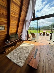 a living room with a tv and a large window at Cabana Azaléia - Vale do Funil in Taió +11 photos