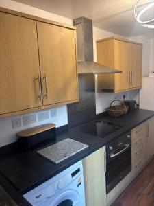 a kitchen with a black counter top with a dishwasher at Morecambe Bay Cottage in Morecambe +4 photos