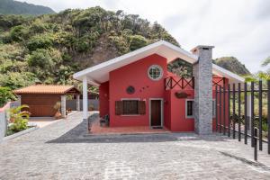 a red house with a mountain in the background at Casa del Mar I by GALMI in Arco de São Jorge