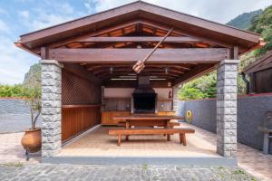a wooden pavilion with a picnic table and a stove at Casa del Mar I by GALMI in Arco de São Jorge