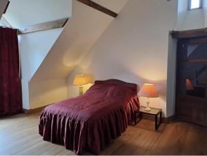 a bedroom with a bed with a red blanket and two lamps at Appartement des écuries in Château-Chervix