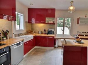 a kitchen with red cabinets and a counter top at Entre ciel et terre in Le Thor