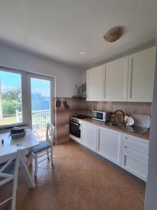 a kitchen with white cabinets and a table and a window at Studio Zora in Goli Breg