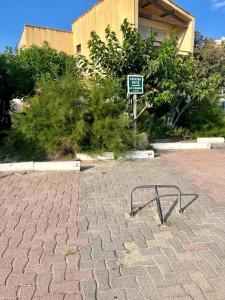 a sign sitting on a brick road next to a building at Studio Cosy à 200m de la plage Wi-Fi in Le Barcarès