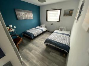 two beds in a room with blue walls at Maison Koh Tao - Chambre chez l habitant - in Langueux