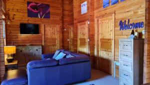 ein Wohnzimmer mit einer blauen Couch und einem Fernseher in der Unterkunft Bramble Bank Gisburn Forest Lodge in Skipton