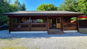 eine große Holzhütte mit einer Veranda und einer Treppe in der Unterkunft Bramble Bank Gisburn Forest Lodge in Skipton