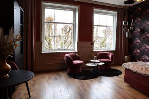 a living room with two chairs and a table and two windows at Stadshotel Geertruidenberg in Geertruidenberg