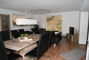 a dining room with a wooden table and black chairs at Ferienwohnungen TalBach in Simmerath