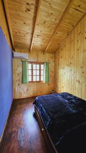ein Schlafzimmer mit einem Bett in einem Holzzimmer in der Unterkunft Cabañas Flores de Lapacho Iguazu in Puerto Iguazú