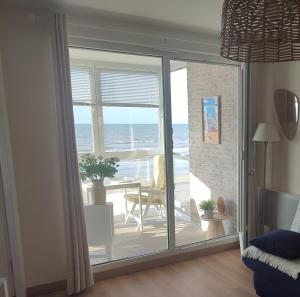 a room with a sliding glass door with a view of the ocean at Vue Panoramique FACE MER in Bray-Dunes +17 photos